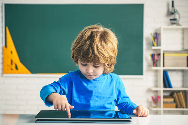 Schoolkid or preschooler learn. Education, school, technology and internet concept - little pupil with tablet pc in school. - 写真・画像