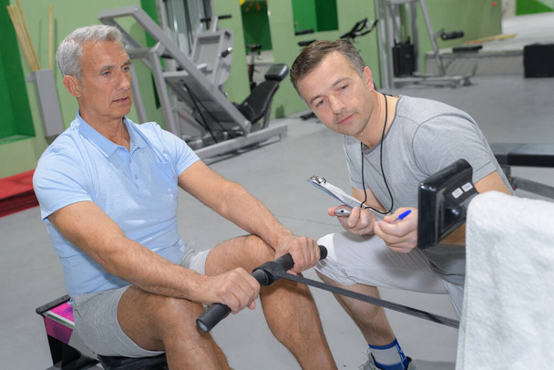 senior man working out in gym with personal trainer - Fotoğraf, Görsel