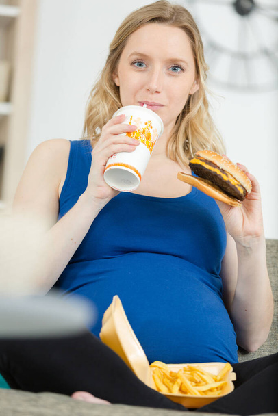pregnant woman with belly is holding a burger - Valokuva, kuva