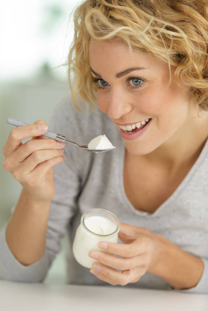 portrait of beautiful young woman eating yogurt at home - Fotoğraf, Görsel