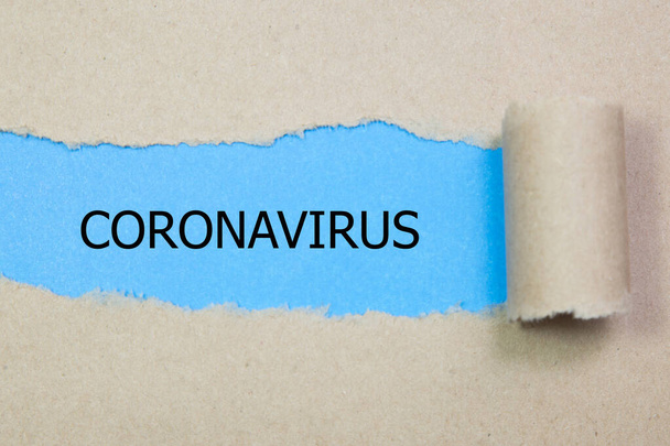 「 CORONAVIRUS 」という言葉が引き裂かれた紙の後ろに現れる - 写真・画像