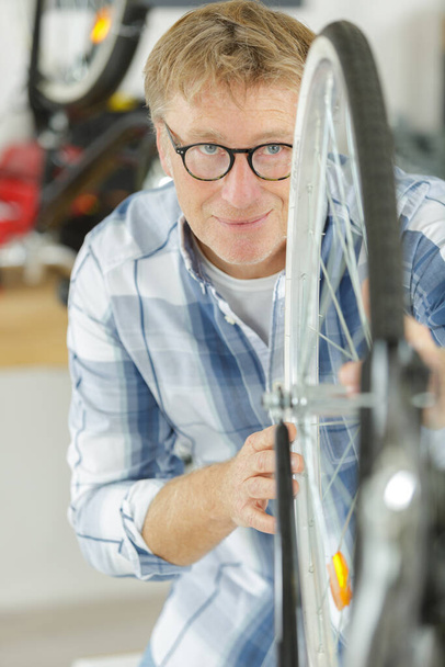 mature man working on bicycle wheel - Photo, Image
