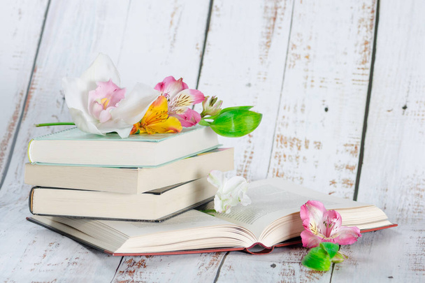 Empilement de manuels sur un fond en bois clair sont décorés de fleurs
 - Photo, image