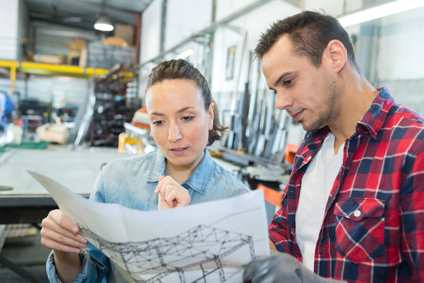 female and male worker looking at plans in warehouse - Photo, image