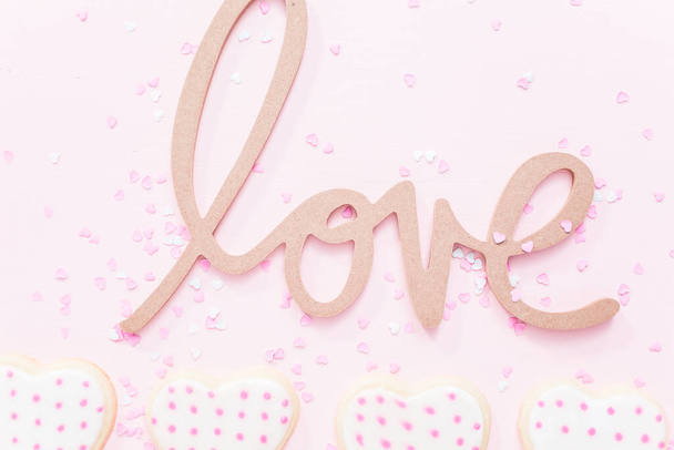 Segno d'amore con biscotti a forma di cuore di zucchero su sfondo rosa
. - Foto, immagini
