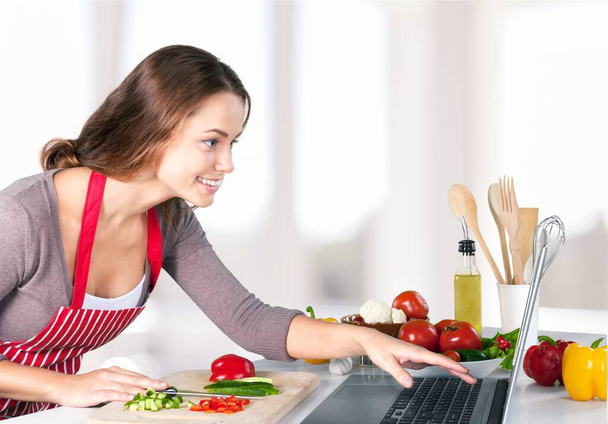 Nainen ruoanlaitto käyttäen reseptiä kannettavasta tietokoneesta
 - Valokuva, kuva