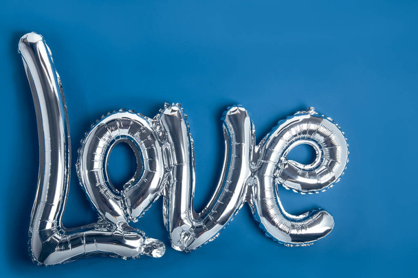 Silver foil balloons in the form of a word Love. Happy Valentine's day. Love festival concept. Balloons make people happy. Classic blue trendy color background isolated. Copy space - Foto, immagini
