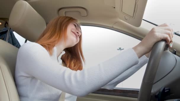 jonge vrouw bestuurder hebben plezier achter het stuur luisteren naar muziek in een auto. - Video
