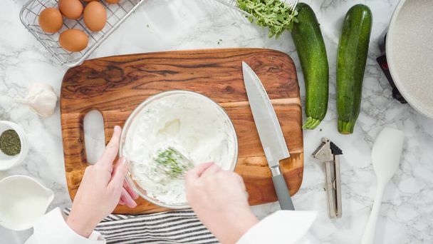 Flat lay. Step by step. Mixing ingredients in a mixing bowl to make zucchini cakes. - Foto, afbeelding