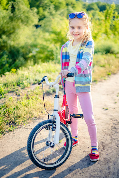 Little girl standing with bike - Photo, image