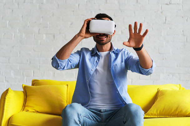 Excited man in virtual reality glasses smiling catching while having VR experience - Fotoğraf, Görsel