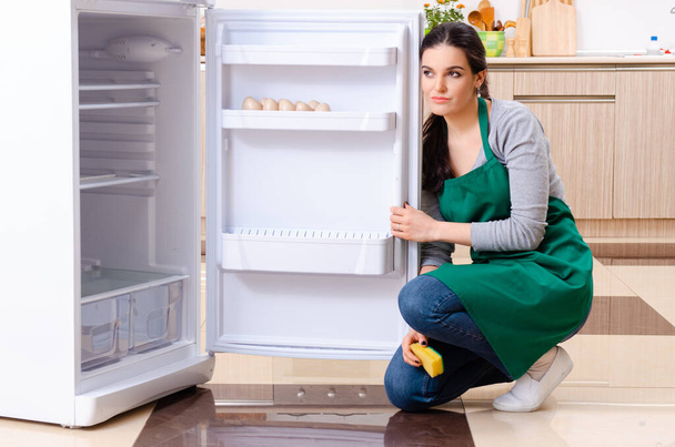 Giovane donna pulizia frigorifero nel concetto di igiene - Foto, immagini