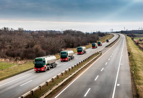 Konvoi oder Karawane von Tanklastwagen oder Zisternen auf einer kurvenreichen Autobahn durch die ländliche Landschaft - Foto, Bild