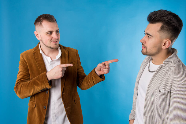 Porträt zweier junger Männer, die miteinander reden, auf blauem Hintergrund  - Foto, Bild