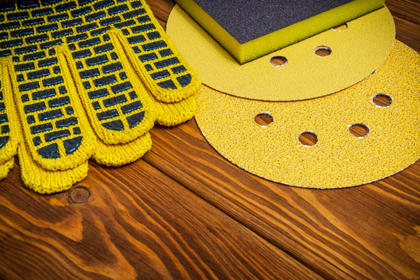 Набір абразивних інструментів і жовтих робочих рукавичок на старовинних дерев'яних дошках майстер використовується для шліфування предметів
 - Фото, зображення