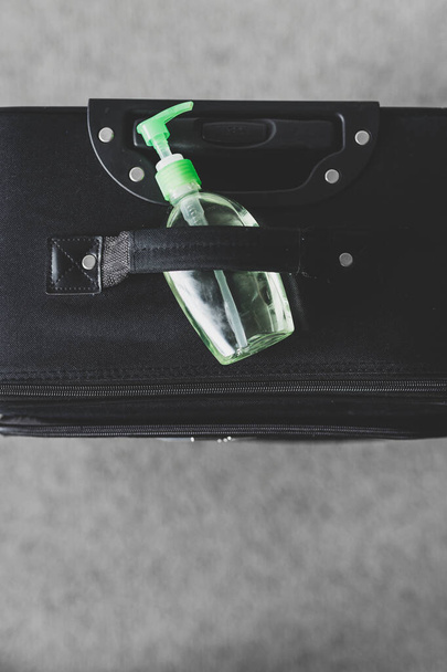 travel safety and hygiene in times of virus outbreak, packing a suitcase with hand sanitizer bottle on top of it - Φωτογραφία, εικόνα