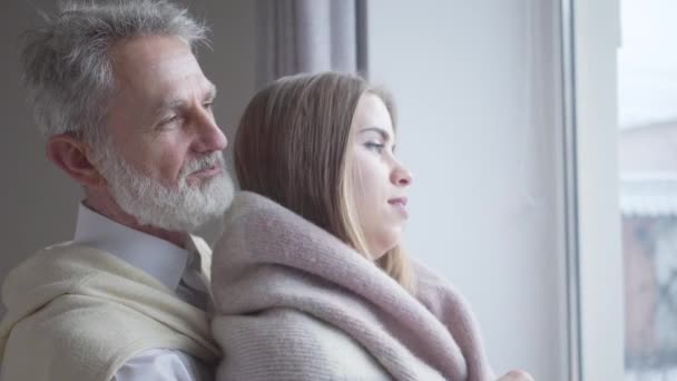 Close-up side view of young pretty Caucasian woman and senior man talking and smiling. Joyful married couple with age difference chatting indoors. Love, unity, leisure, lifestyle. - Záběry, video