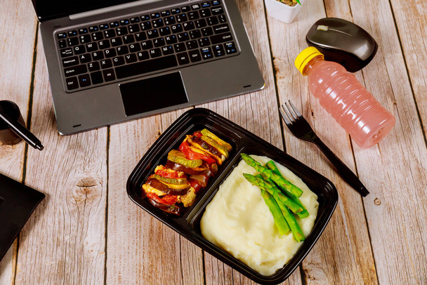 Рататуй из овощей с картофельным пюре, спаржа в контейнере и напитки на обед в офисе
. - Фото, изображение