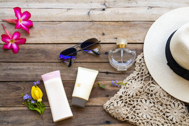 αντηλιακό spf50, λοσιόν σώματος, άρωμα, γυαλιά ηλίου, καπέλο και πλέξιμο της γυναίκας lifestyle χαλαρώστε διάταξη επίπεδη lay στυλ στο φόντο ξύλινο - Φωτογραφία, εικόνα