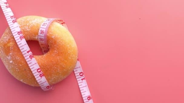 close up of measurement tape and donuts on pink background  - Záběry, video