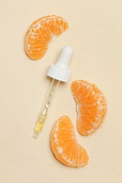 Óleo essencial de tangerina, pipeta conta-gotas e fatias de tangerina
 - Foto, Imagem