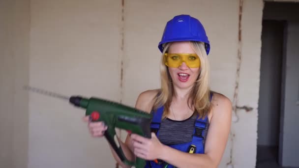 Young sexy female builder with an electric tool. Portrait of a builder woman. - Footage, Video