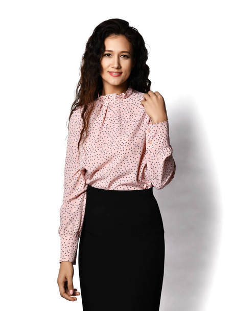 Portrait of smiling young beautiful brunette woman office worker in formal wear polka dot blouse and pencil skirt - Fotó, kép