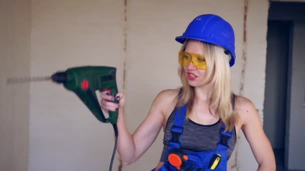 Gyönyörű nő építő egy elektromos kalapács fúró. - Felvétel, videó