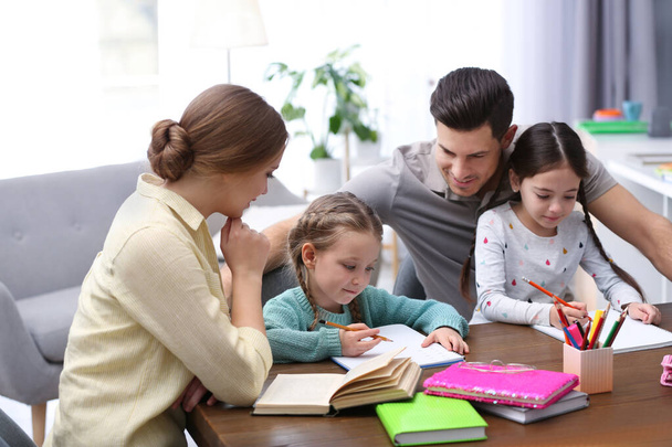 Parents helping their daughters with homework at table indoors - Foto, Imagen