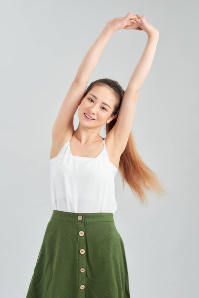 Молодая красивая азиатка улыбается энергичным движением и руки вверх на белом фоне
. - Фото, изображение