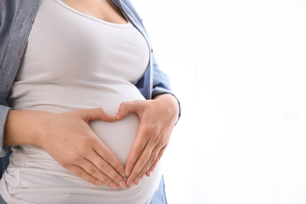 Young pregnant woman on light background, closeup. Space for text - Φωτογραφία, εικόνα