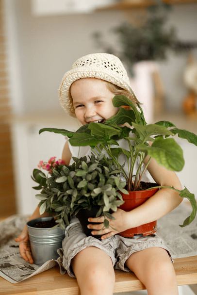 little girl with indoor flowers into pot - Фото, зображення