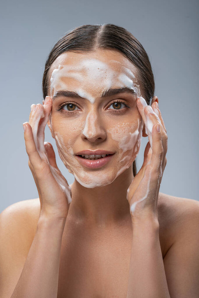 Happy pretty woman washing her face with soap - Φωτογραφία, εικόνα