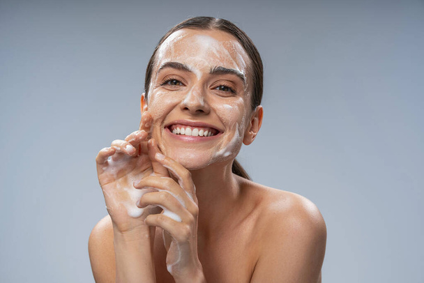 Happy Caucasian woman washing face with white soap - Zdjęcie, obraz