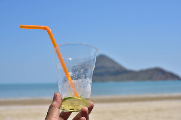 Πρόσωπο που κρατά γυαλί με χυμό στη θάλασσα παραλία - Φωτογραφία, εικόνα