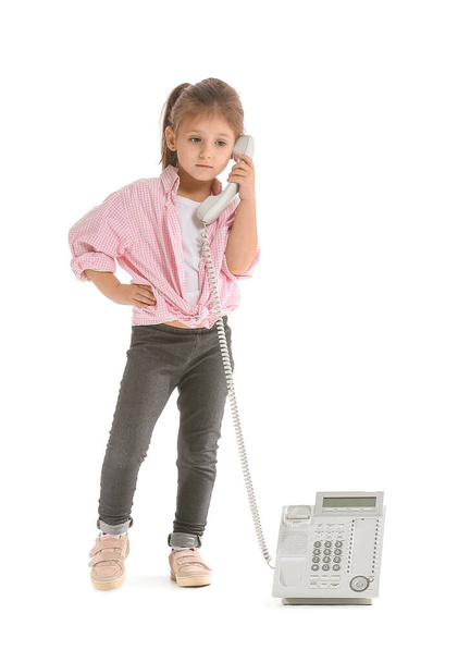 Funny little girl talking by telephone on white background - Fotoğraf, Görsel