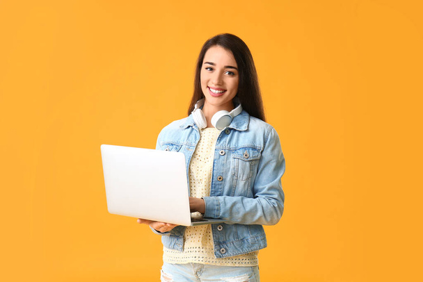 Mooie jonge vrouw met laptop op kleur achtergrond - Foto, afbeelding