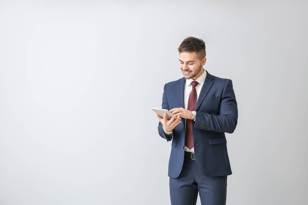 Hombre de negocios guapo con Tablet PC sobre fondo claro
 - Foto, Imagen