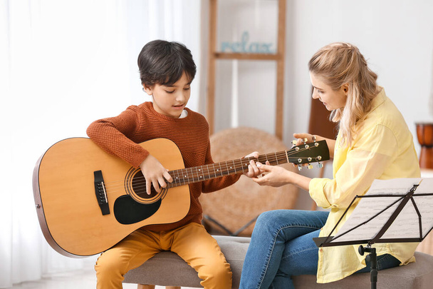Private music teacher giving guitar lessons to little boy at home - Foto, immagini