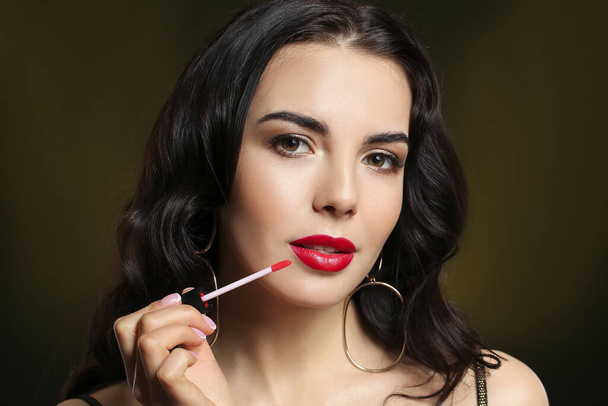 Beautiful young woman with lipstick on dark background - Φωτογραφία, εικόνα
