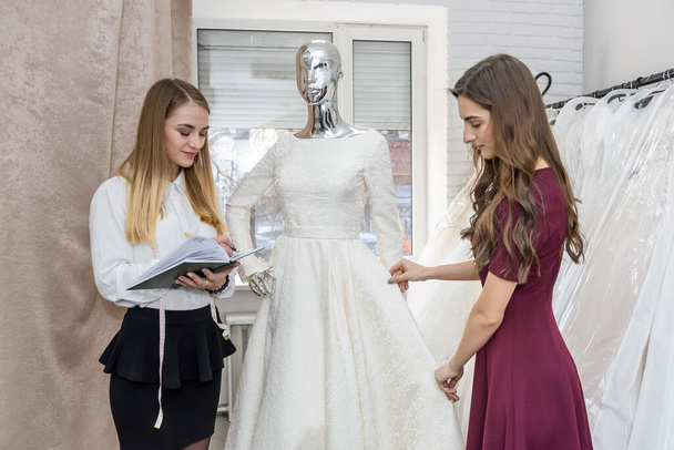 Menyasszony esküvői boltban szabóval és esküvői ruhával - Fotó, kép