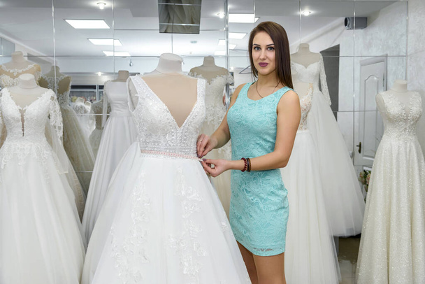 Designer measure dress on a mannequin in bridal shop - Photo, Image