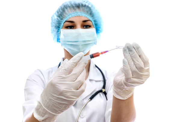 Mladá žena v lékařské uniformě s injekční stříkačkou izolovanou na bílém - Fotografie, Obrázek