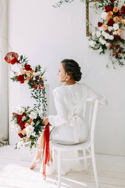 Κόκκινη διακόσμηση με τριαντάφυλλα. Πορτρέτο της νύφης στο ύφος της τέχνης. Το πρωινό της νύφης στο χιονισμένο στούντιο.  - Φωτογραφία, εικόνα