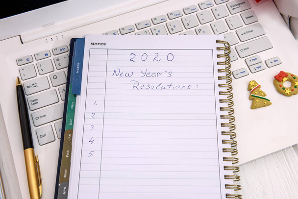Rozdzielczość noworoczna w notatniku z laptopem na stole - Zdjęcie, obraz