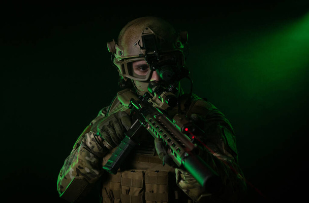 um soldado em roupas militares com um dispositivo de visão noturna e em um fundo escuro
 - Foto, Imagem