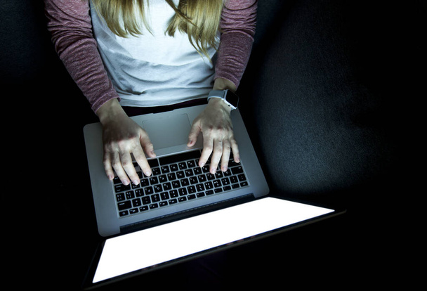 Женщина работает допоздна сидя на диване с ноутбуком
 - Фото, изображение