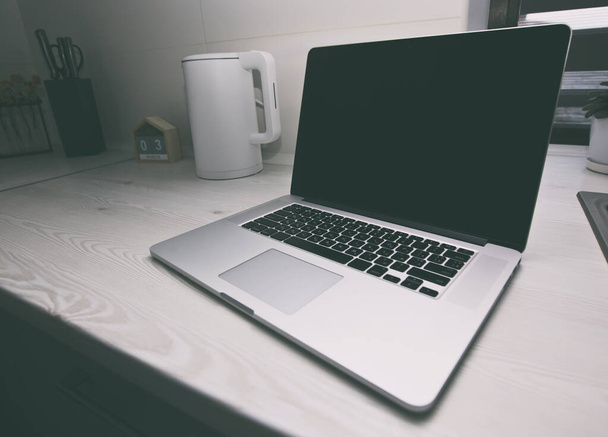 A modern laptop a fa asztalon a konyhában. Koncepció a receptek kereséséről, az összetevők megrendeléséről és a weben való szörfözésről - Fotó, kép