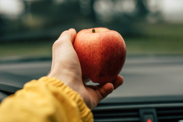 Light apple snack in the car, male hand take ripe fruit - Foto, immagini