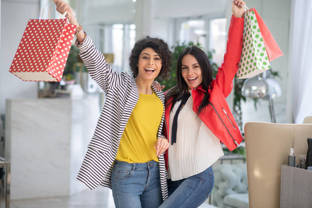 Two beautiful women feeling happy holding shopping bags - Valokuva, kuva